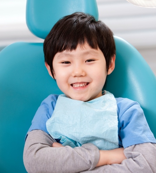 Little boy smiling with arms folded in dental chair