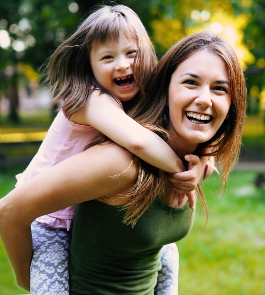 Mom giving daughter a piggyback ride outside