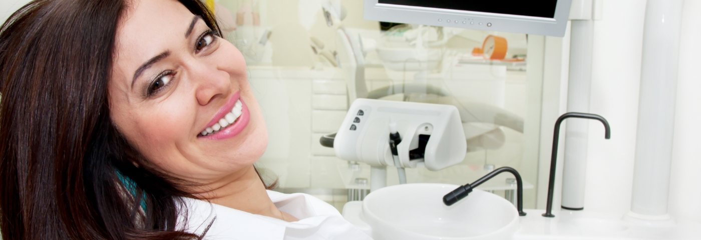 Female patient in dental office leaning back and smiling