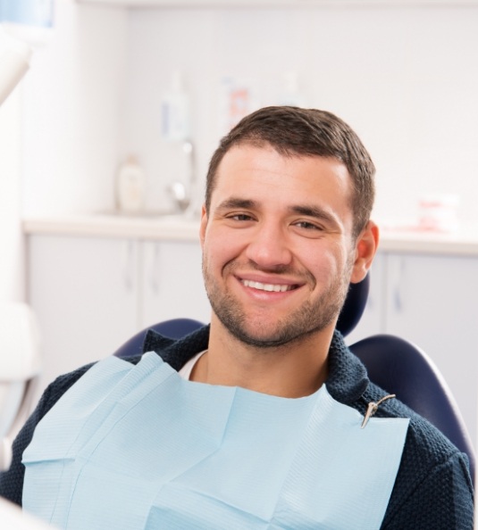 Man with facial hair sitting in dental chair smiling