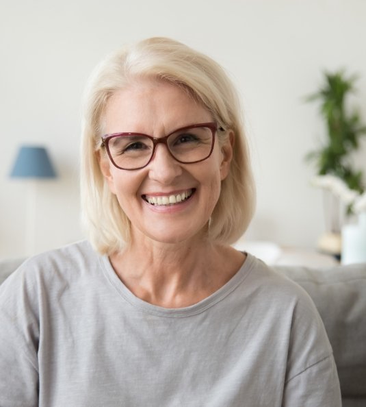 Woman with glasses sitting on couch and smiling