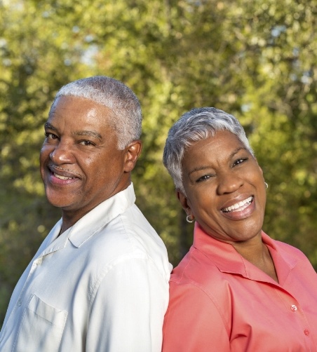 Man and woman standing back to back outside smiling