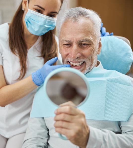 Man using dental mirror provided by dentist to check smile