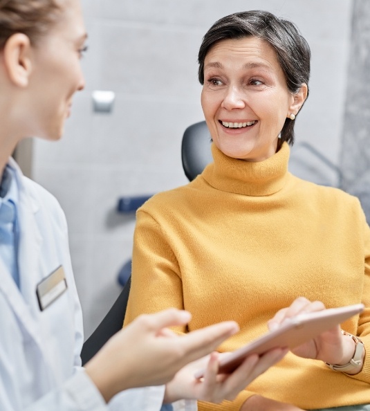 Female patient in yellow sweater talking to dentist