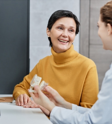 Woman in yellow sweater looking at dentist and smiling