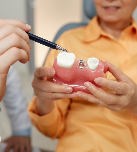 Patient holding model of dental implant between teeth