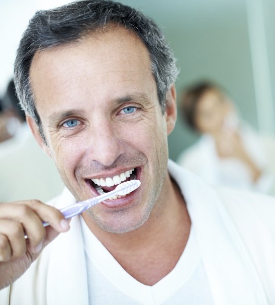 Man in white shirt brushing his teeth