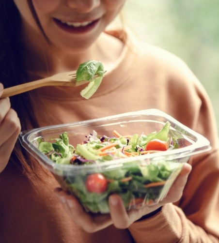 Woman holding and eating a salad