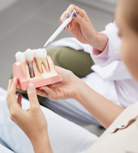 Dentist showing patient a dental implant model