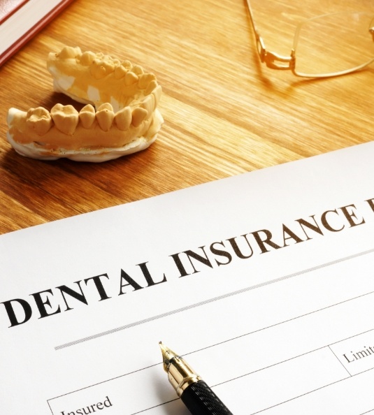 Dental insurance form with pen model teeth and other items