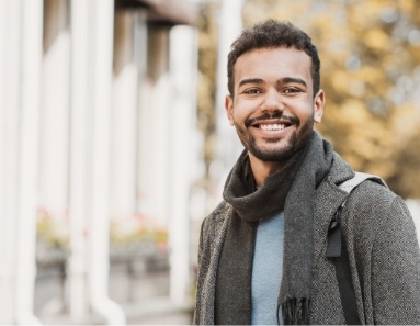 Man in grey jacket smiling outside