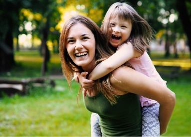 Woman giving little girl a piggyback ride outside