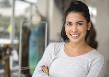 Woman in grey shirt smiling with arms folded