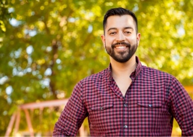 Man in patterned shirt smiling outside