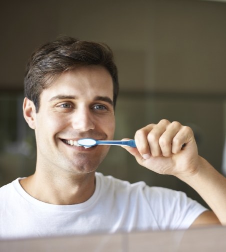 Man in white shirt brushing his teeth