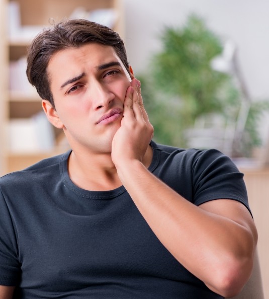 Man sitting on couch with tooth pain