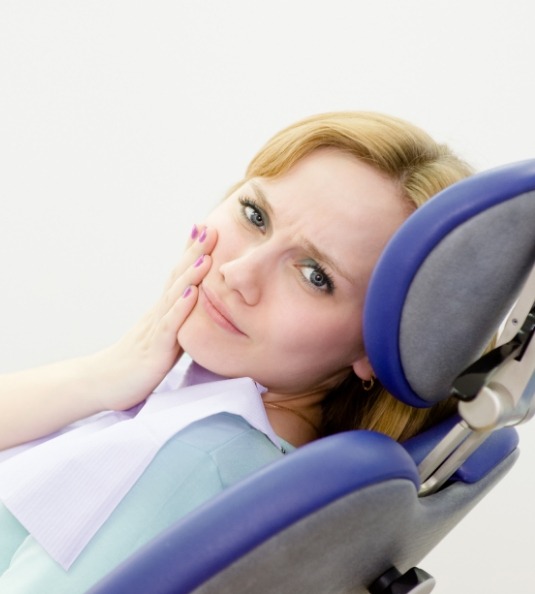 Woman leaning back in dental chair with tooth pain