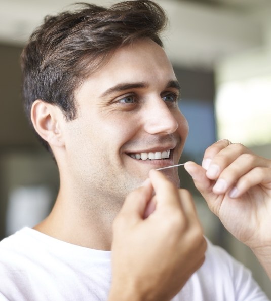 Man in white shirt holding dental floss