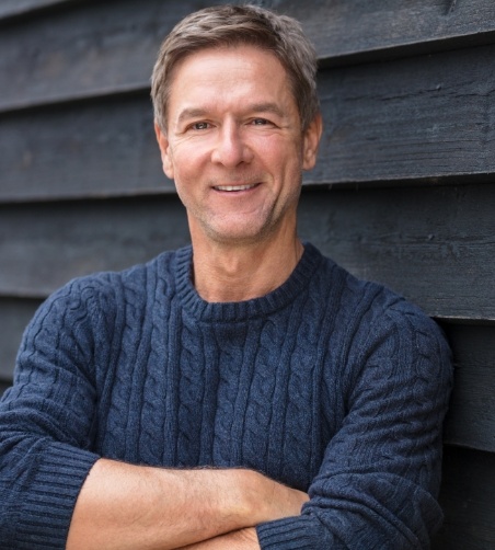 Man in blue shirt smiling with arms folded