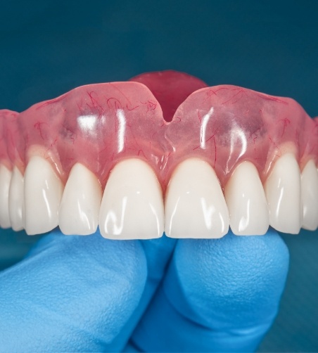 Close up of gloved hand holding a full denture