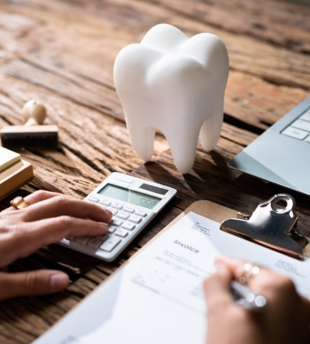 Tooth sitting on table while person fills out form and uses calculator