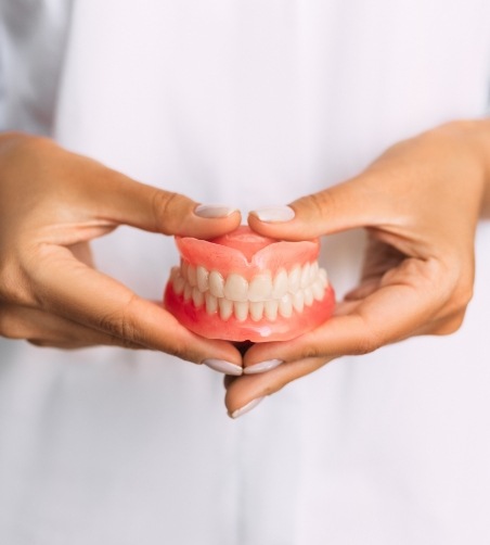 Close up of full dentures held by two hands