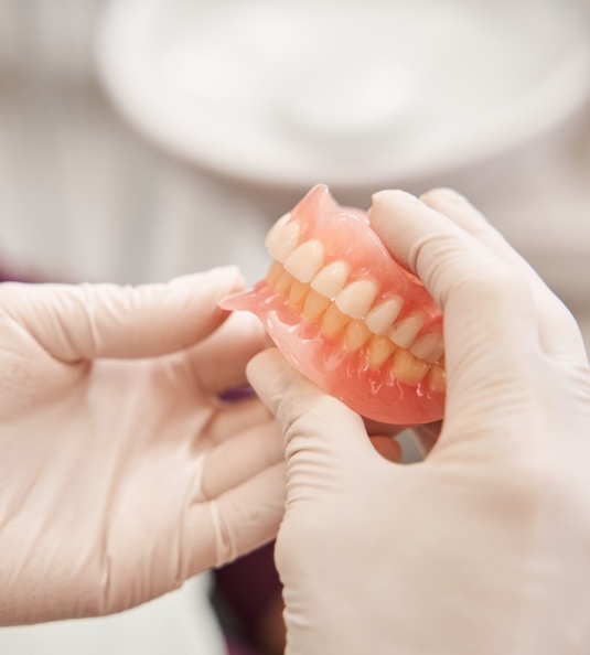 Gloved hand holding full dentures