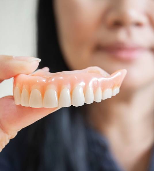 Close up of woman holding a full denture