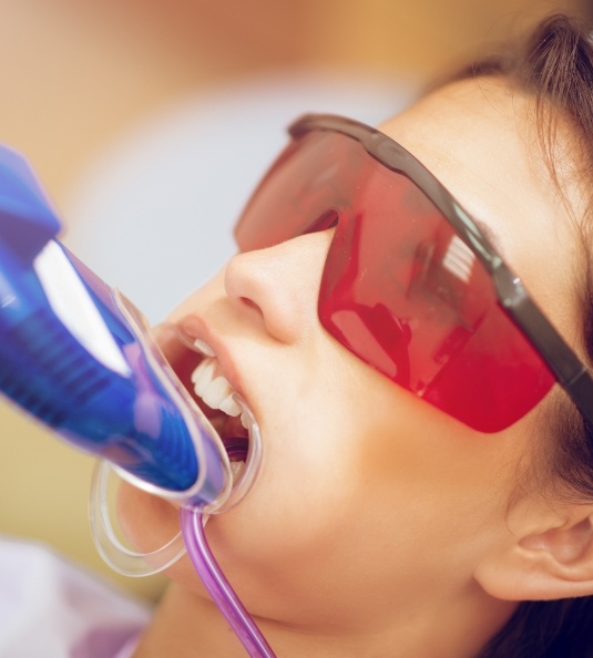 Female patient with protective glasses receiving fluoride treatment