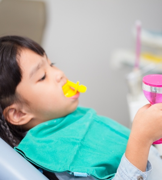 Young child receiving fluoride treatment and holding a toy