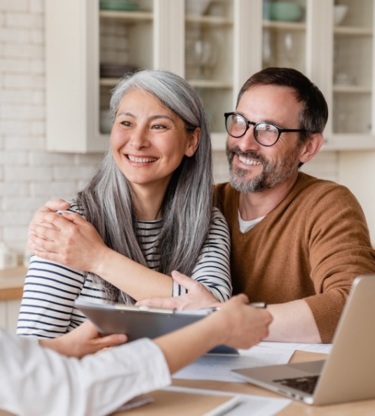 Man and woman sitting at table speaking to someone