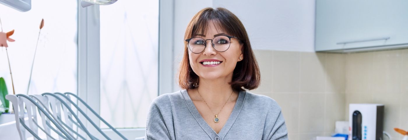 Woman in glasses sitting in chair and smiling