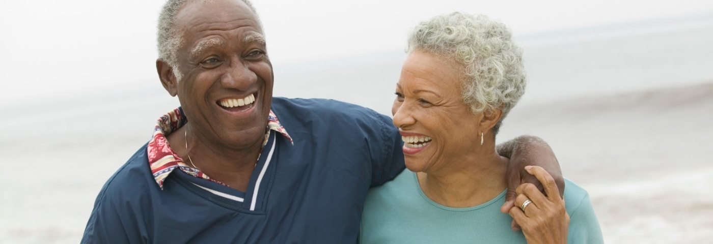 Man and woman smiling with man putting arm around woman