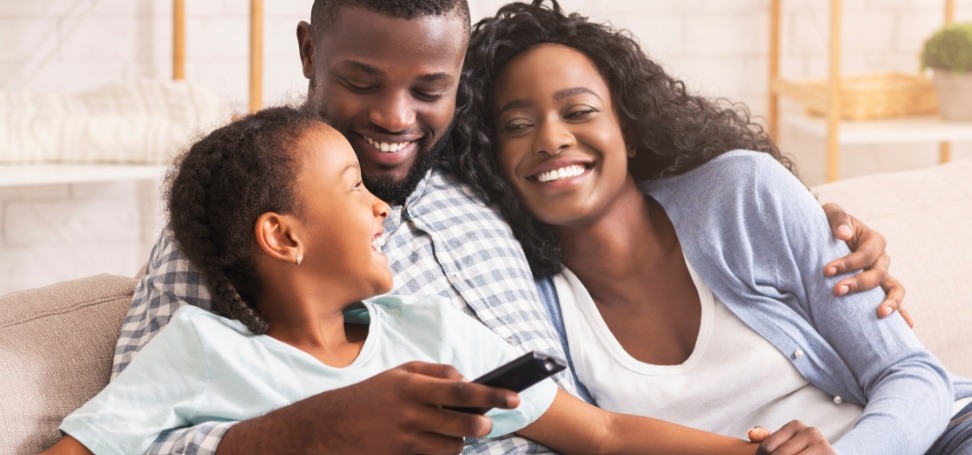 Man hugging wife and daughter on couch