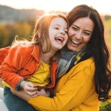 Woman holding daughter outside and smiling