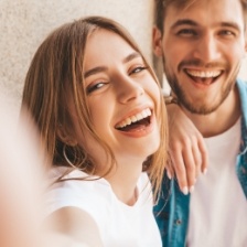 Man and woman standing next to wall and laughing