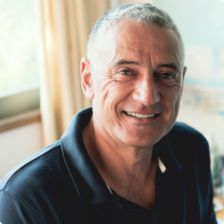 Older man in collared shirt smiling in house