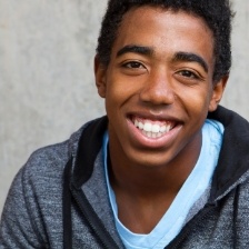 Boy in hoodie standing outside and smiling