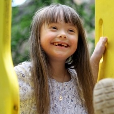 Little girl with missing teeth smiling on playground equipment