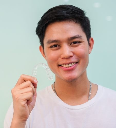 Man in clear shirt holding clear aligner