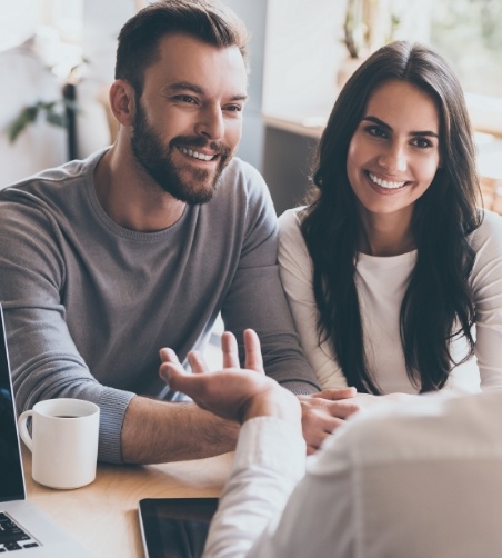 Man and woman speaking to dentist across desk