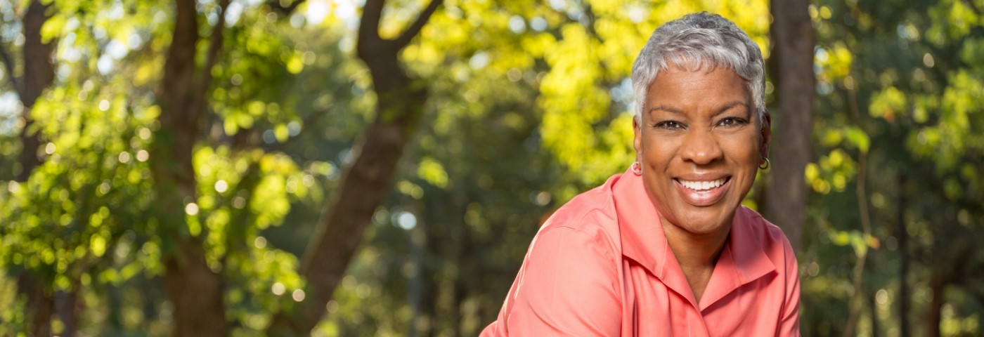 Woman in peach colored shirt outside smiling