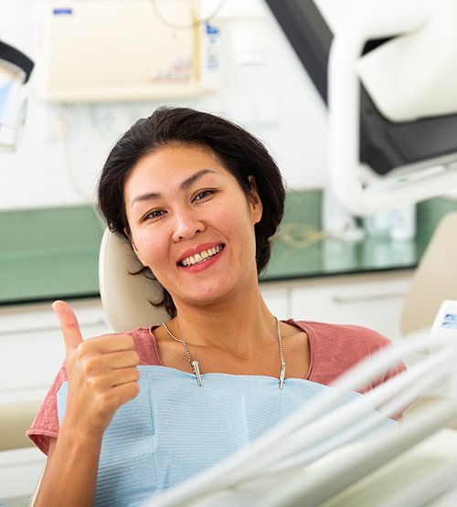 Smiling woman in dentist’s office giving thumbs up