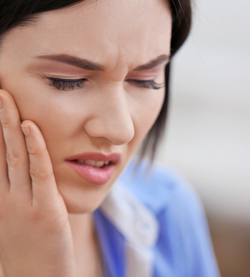 Close up of woman rubbing her jaw in pain