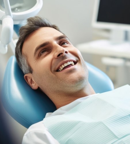 Man leaning back in dental chair and smiling