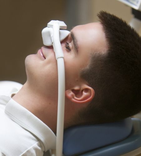 Man leaning back in dental chair with nasal mask