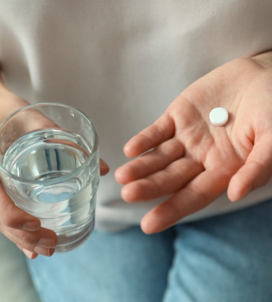 Holding a glass of water and a pill