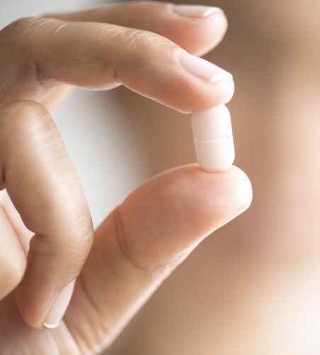 Close up of pill held between fingers