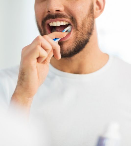 Man with beard brushing his teeth