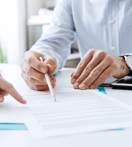 Man in button up shirt pointing to form with pen